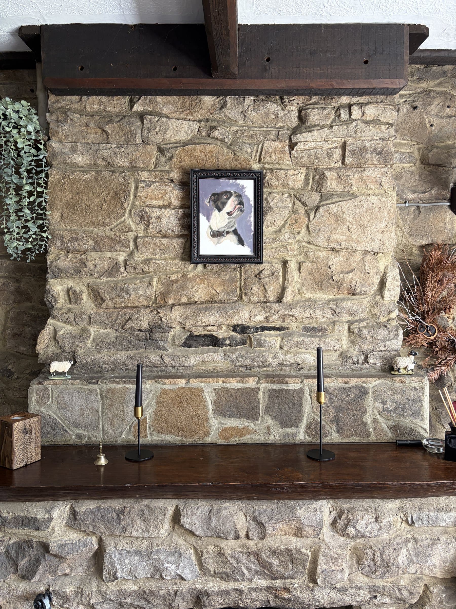 A small framed dog portrait displayed on a stone wall