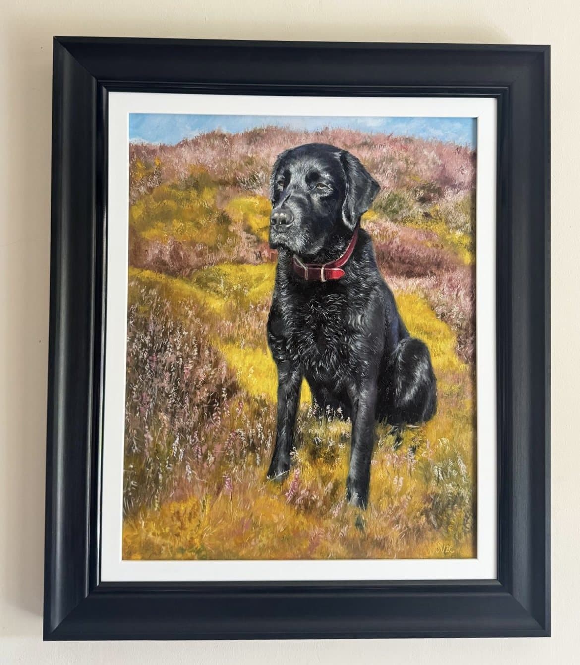 Painting of a black Labrador sitting in a colourful moorland landscape