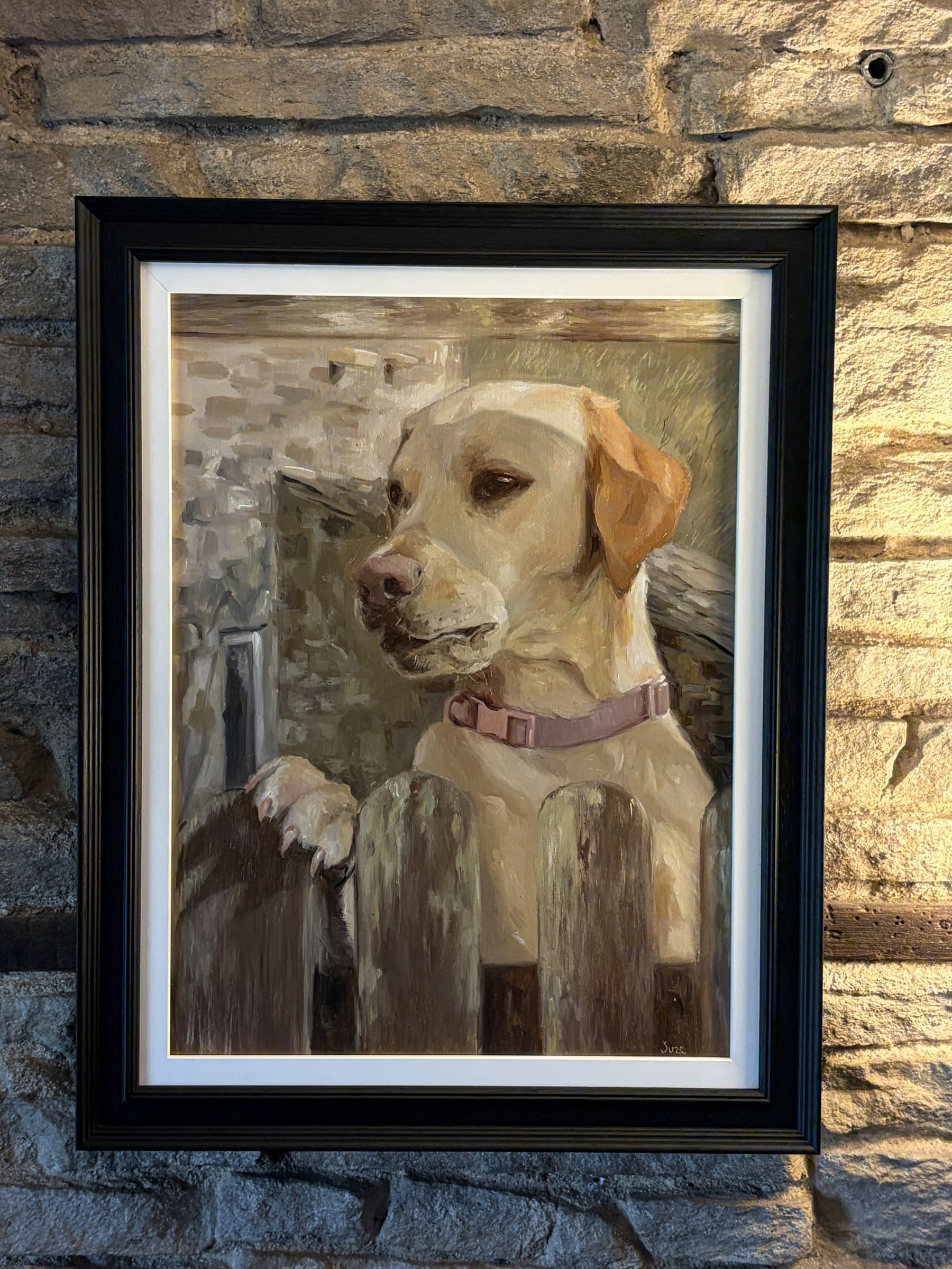 Framed painting of a yellow Labrador resting its paws on a ledge